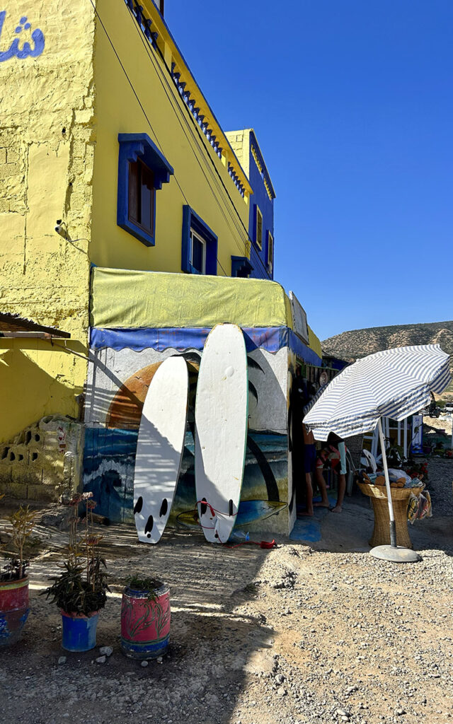 Vibrant street scene in Aghroud with multicolored facades and blue sky background.