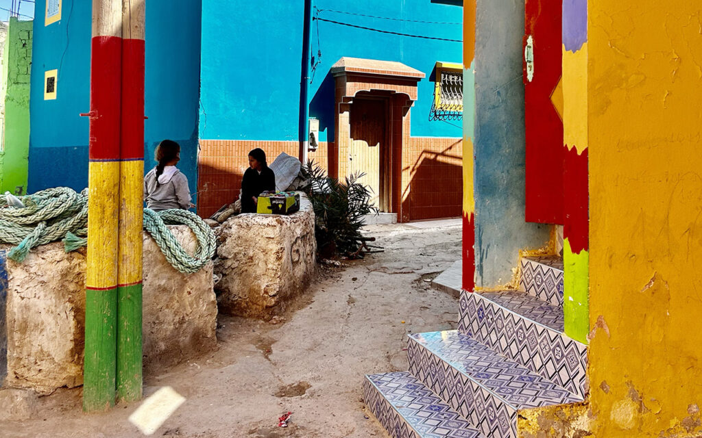 Contrast of bright rainbow houses and the deep blue Atlantic ocean in Aghroud.