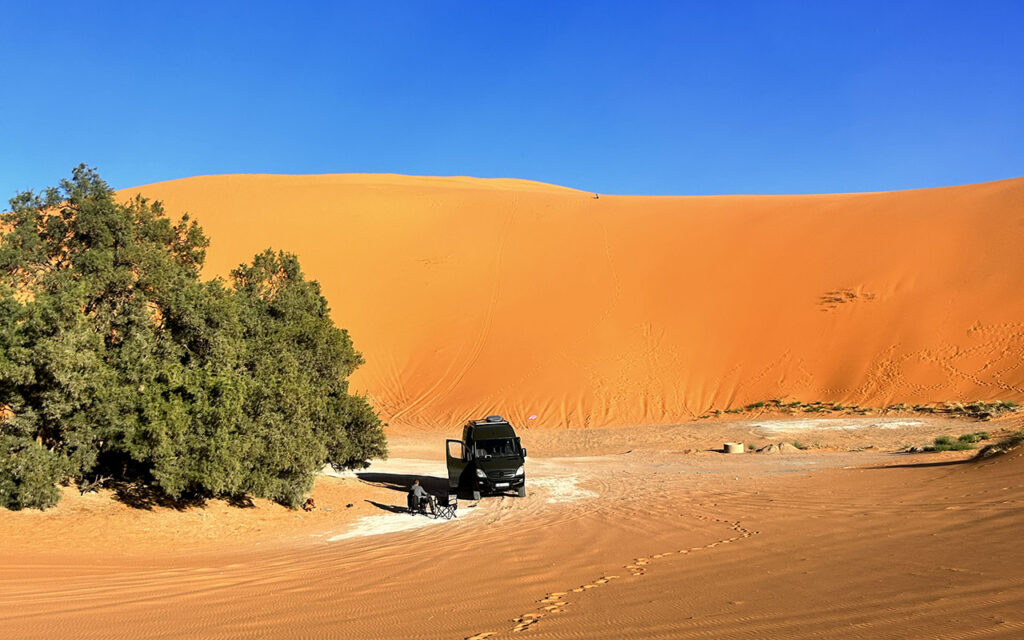 Sahara deserve and vanlife – a 4x4 sprinter in the middle of dunes.
