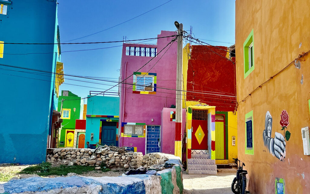 Vibrant street scene in Aghroud with multicolored facades and blue sky background.