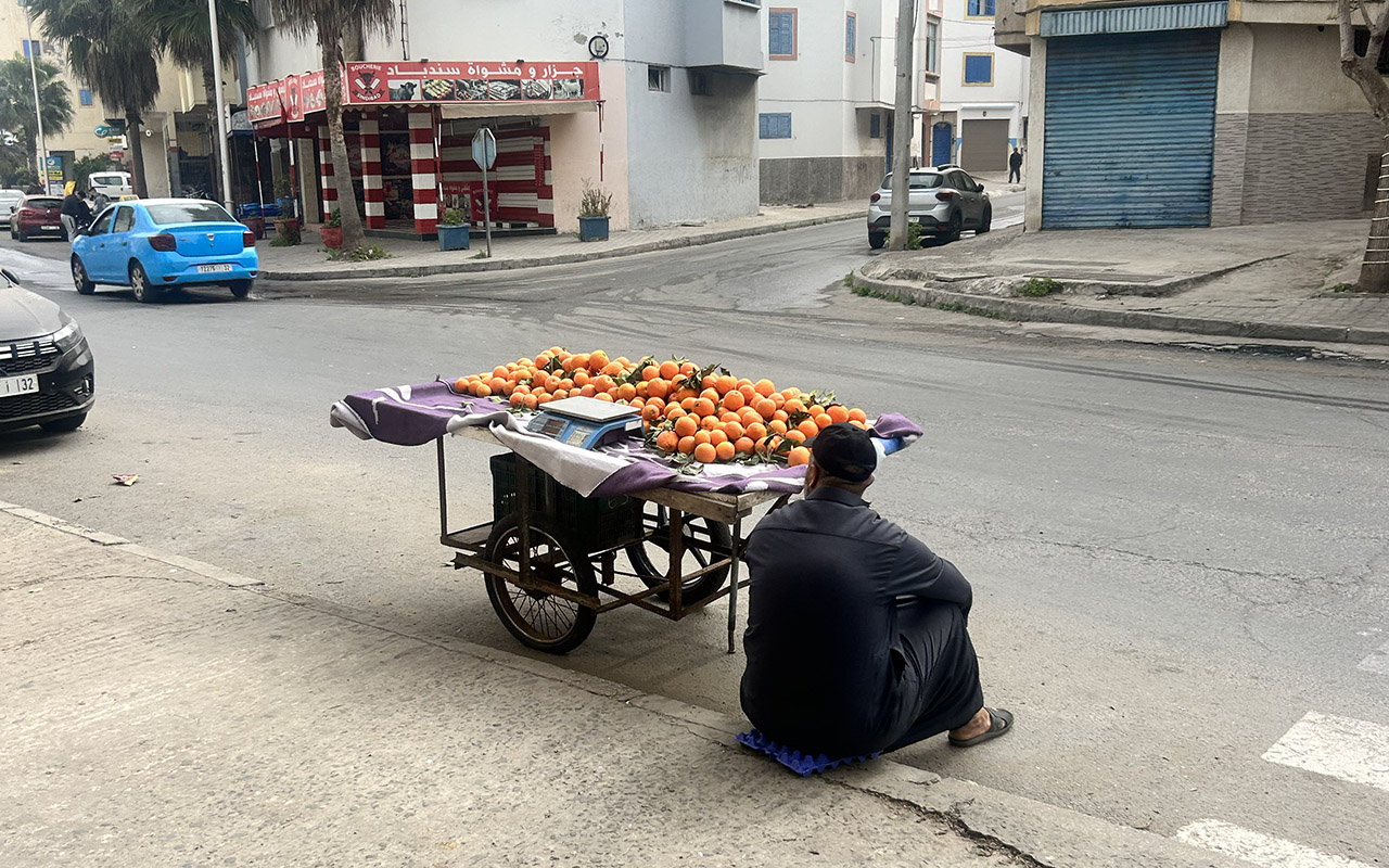 Man selling oranges on street in Morocco.