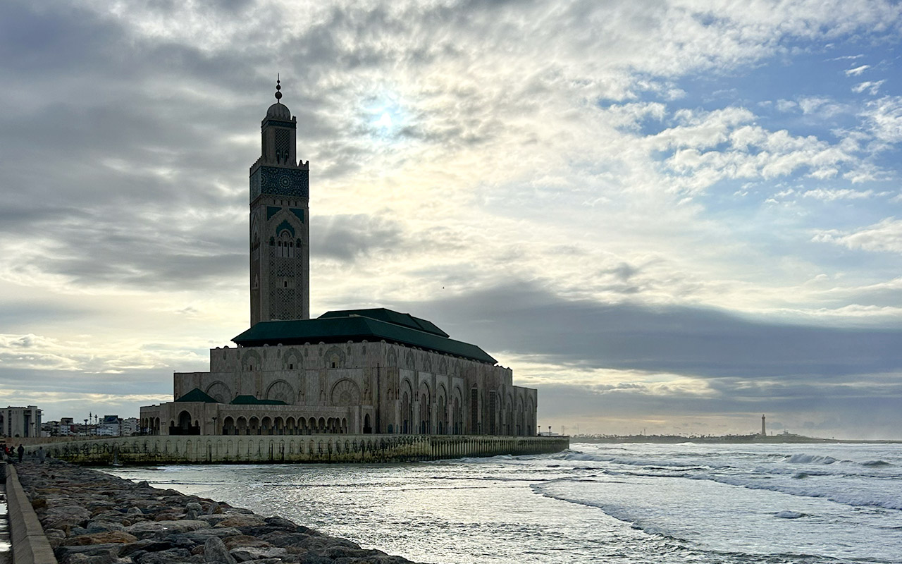 Hassan II Mosque in Casablanca by the Atlantic Ocean with waves and cloudy sky