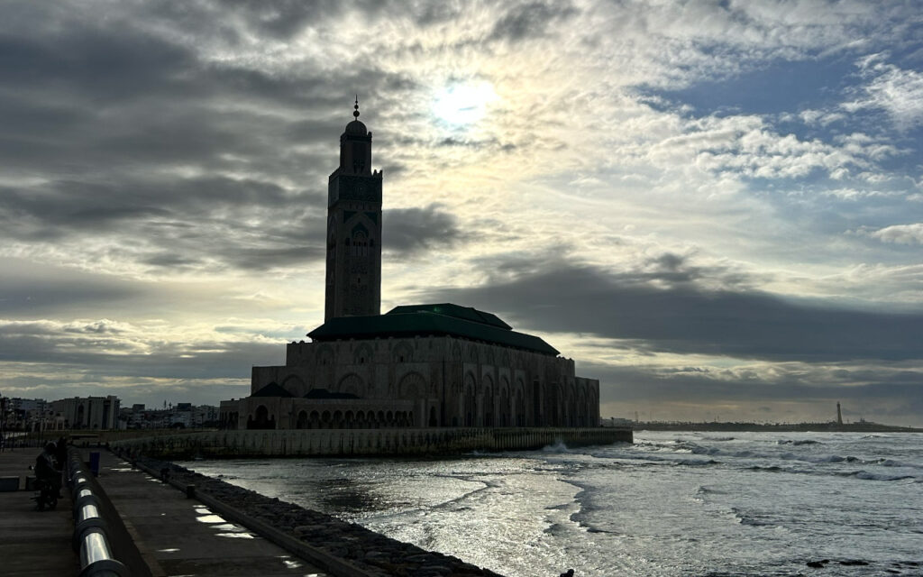 Hassan II Mosque in Casablanca by the Atlantic Ocean at sunset with dramatic clouds and reflections

