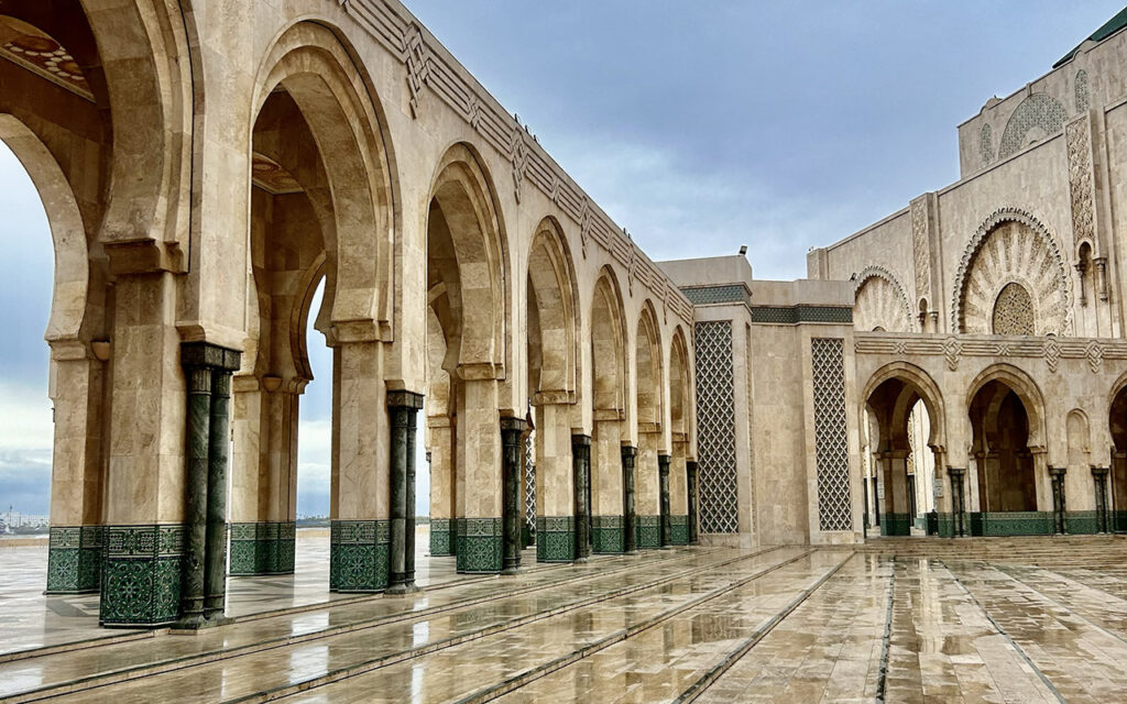 Courtyard arches of Hassan II Mosque in Casablanca with wet floor and reflections