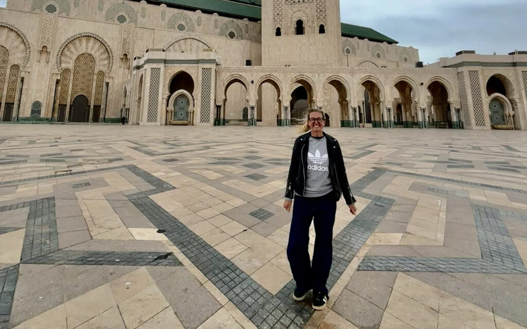 Visitor standing in the courtyard of Hassan II Mosque in Casablanca with arches and detailed facade in the background