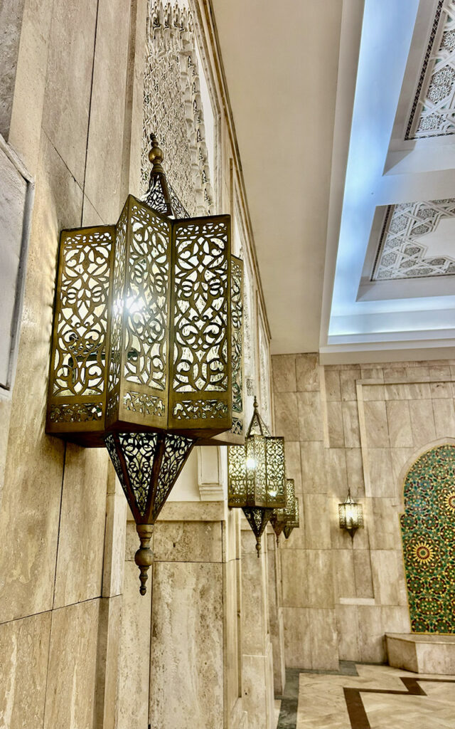 Traditional Moroccan lanterns on the wall inside Hassan II Mosque in Casablanca with intricate patterns and warm light