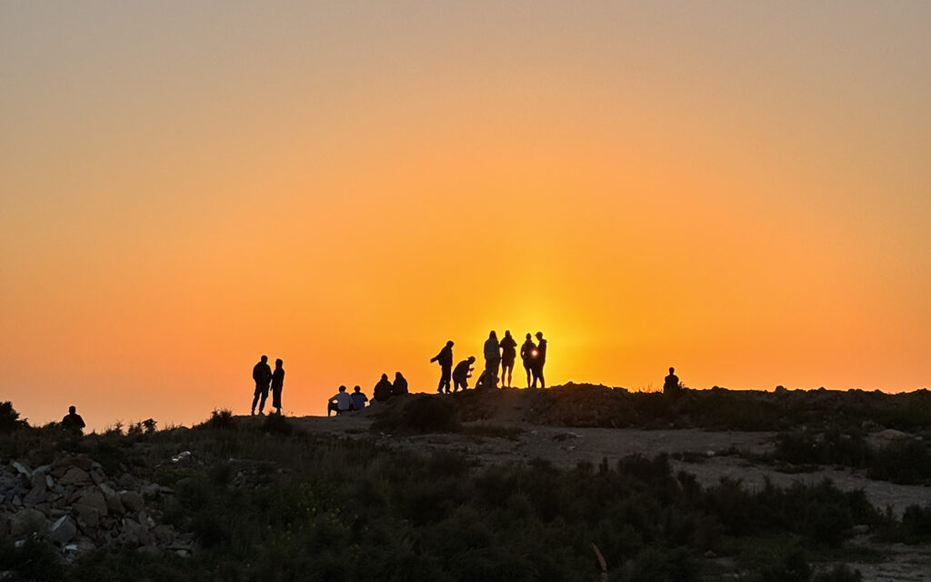 Large crowd gathered at Taghazout skatepark watching skaters during sunset, Morocco