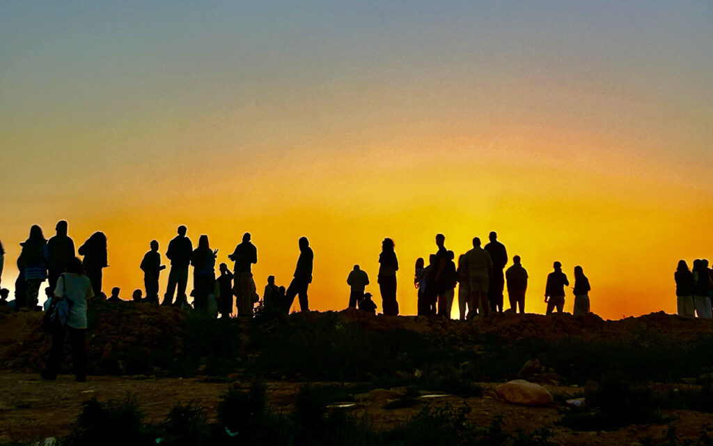 Large crowd gathered at Taghazout skatepark watching skaters during sunset, Morocco