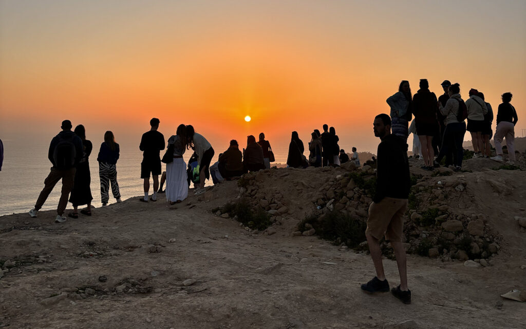 Large crowd gathered at Taghazout skatepark watching skaters during sunset, Morocco