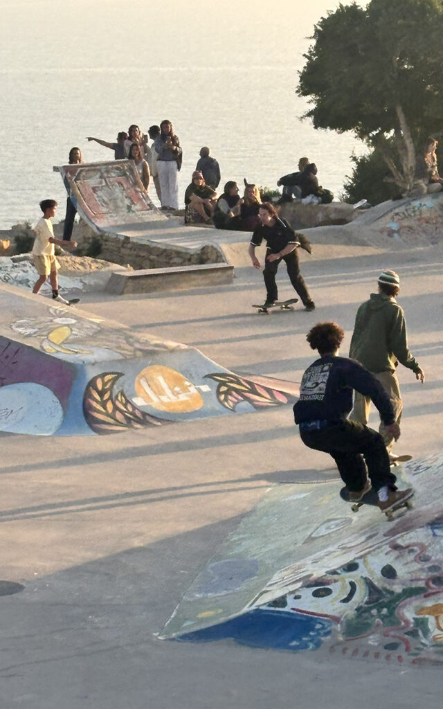 Skaters and crowd at Taghazout skatepark with ocean view at sunset, Morocco